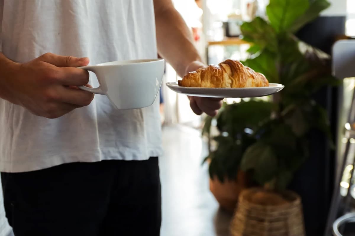 Carrying a coffee and a butter croissant to a table