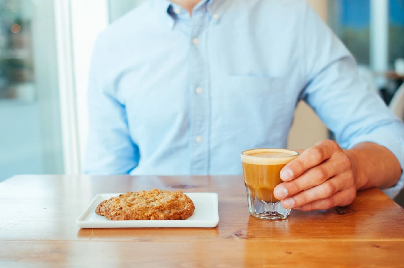 Cortado in a glass and an oatmeal cookie on the table